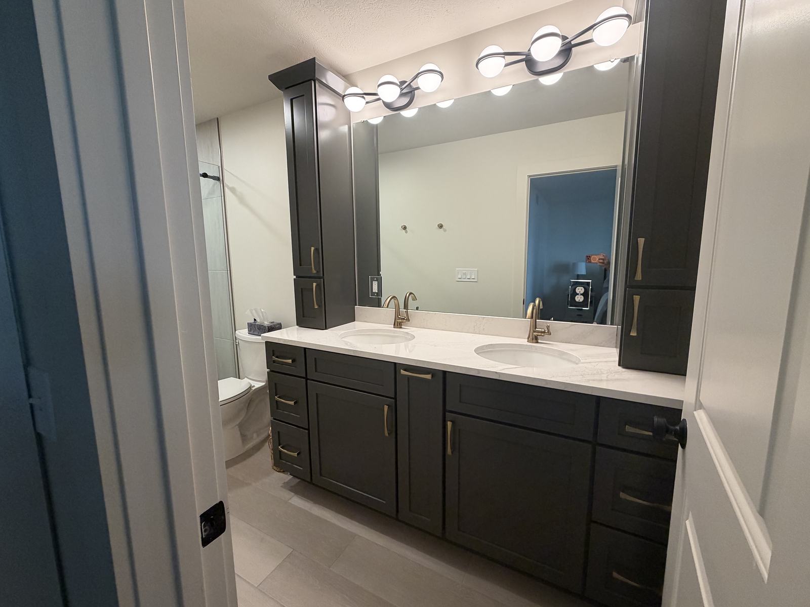 Espresso double vanity with a linen tower, quartz top and brushed gold faucets