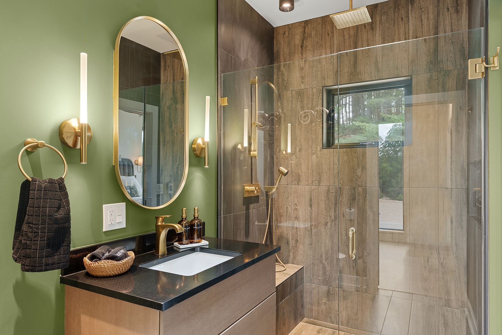 Green bath with a wood-look tile shower, brass fixtures and floating vanity