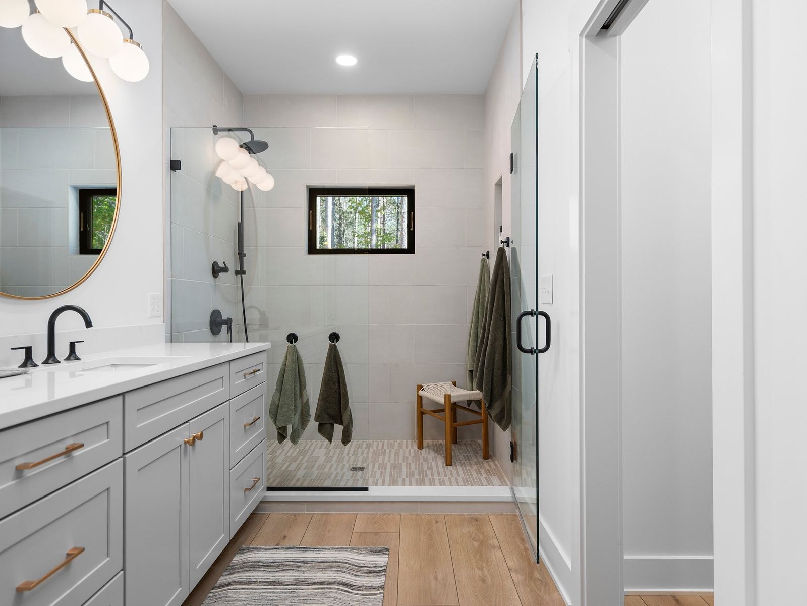 Grey vanity bath with a curbless shower and mosaic shower floor