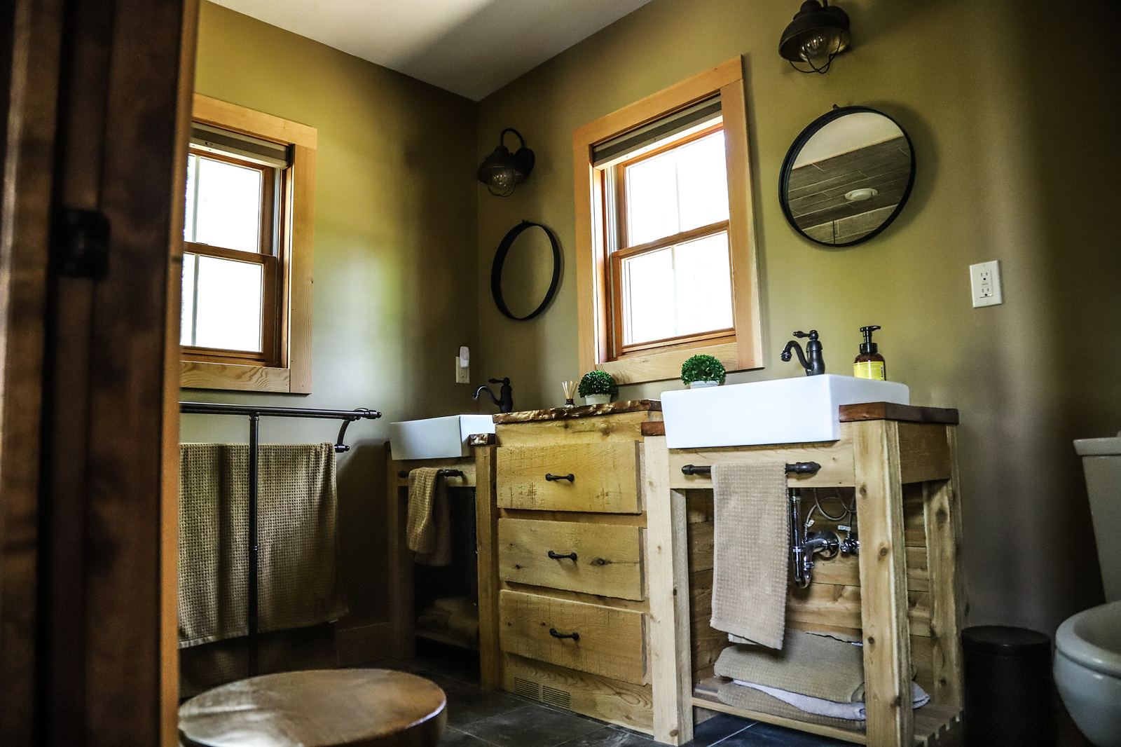 Olive bath with reclaimed wood vanities, farmhouse sinks and slate floors