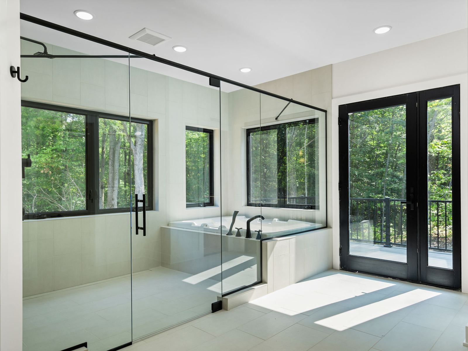 Spa bath with a glass shower enclosure, soaking tub and forest views