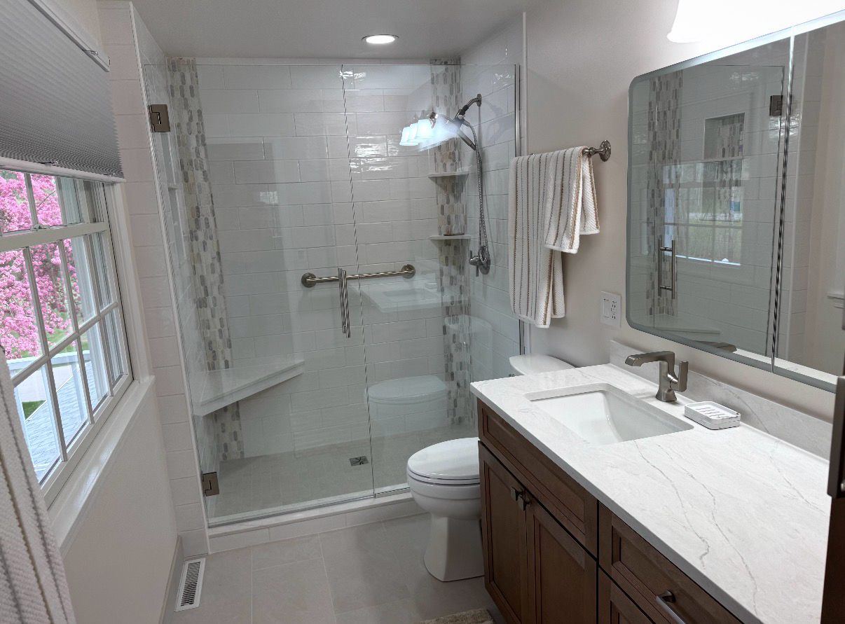 Bright bath with a glass shower, wood vanity and marble-look quartz top