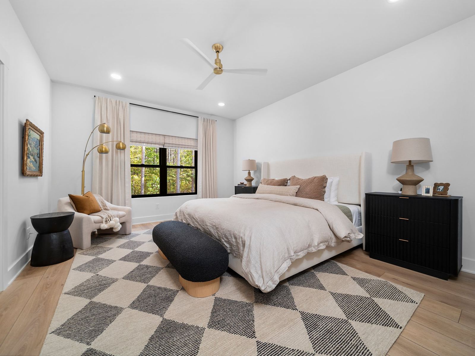 Primary bedroom with a linen bed, black dressers and a checkered wool rug