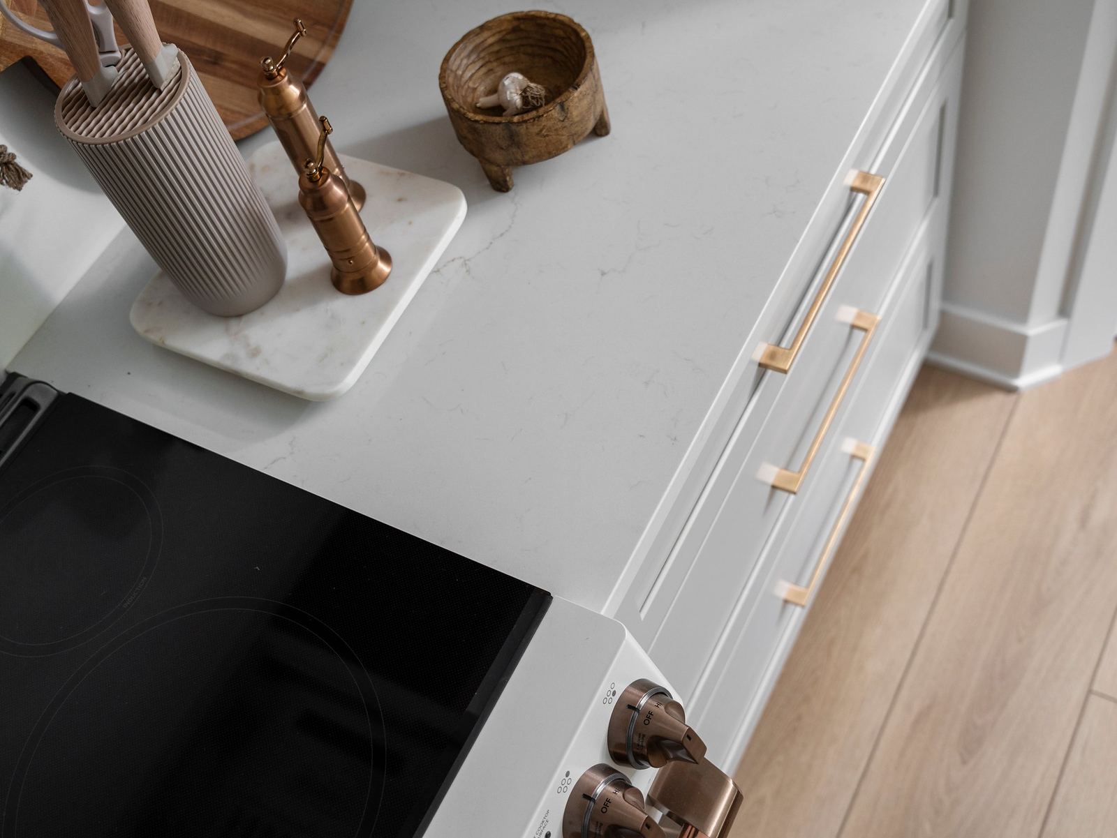 Quartz countertop detail beside an induction cooktop with copper knobs