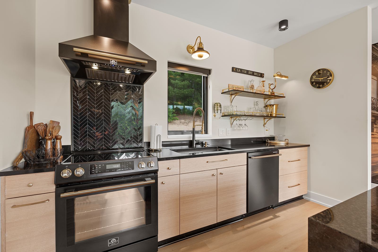 Range wall with a mirrored chevron backsplash, bronze hood and brass shelving