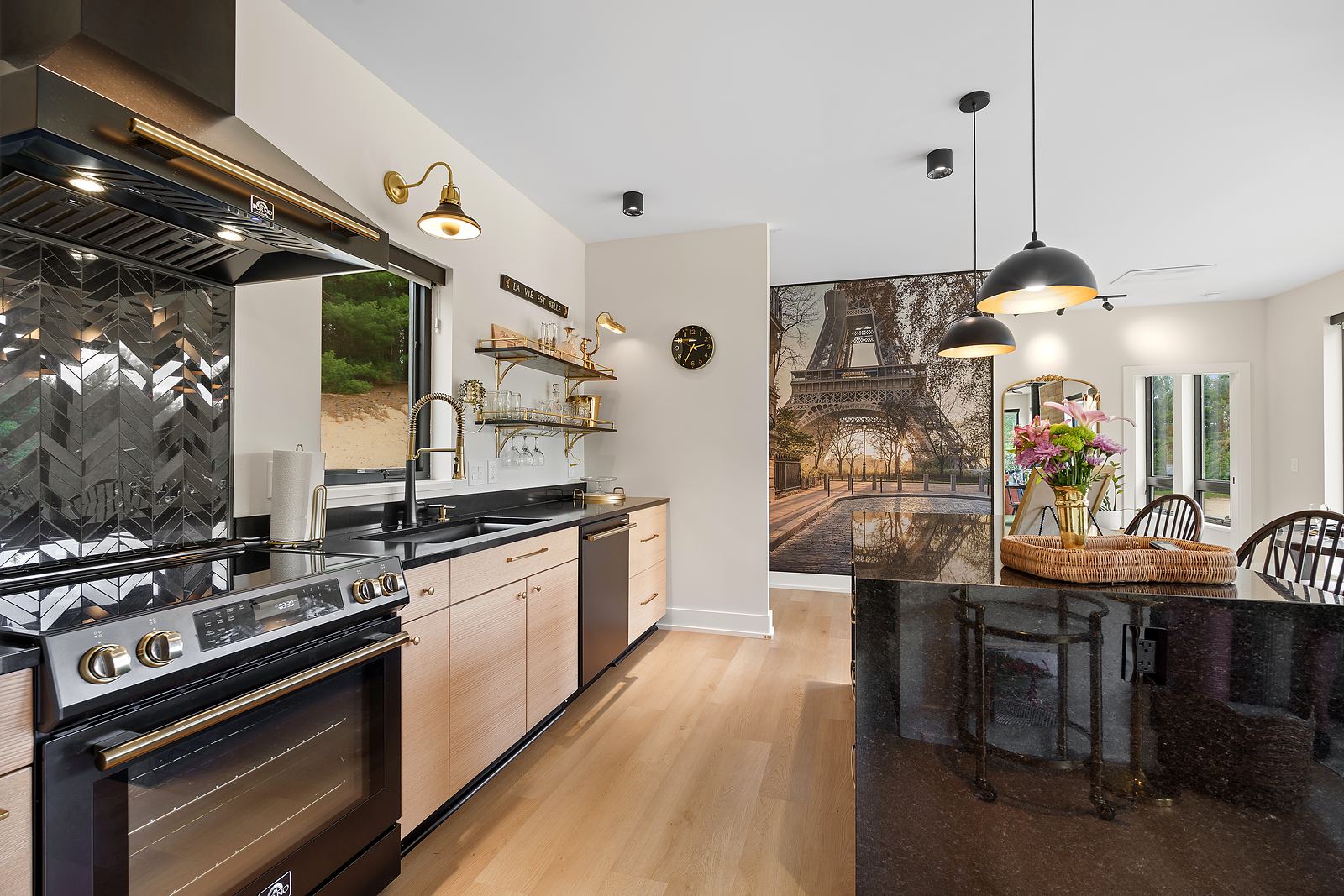 Black and brass kitchen with rift oak cabinetry, chevron tile and a granite island