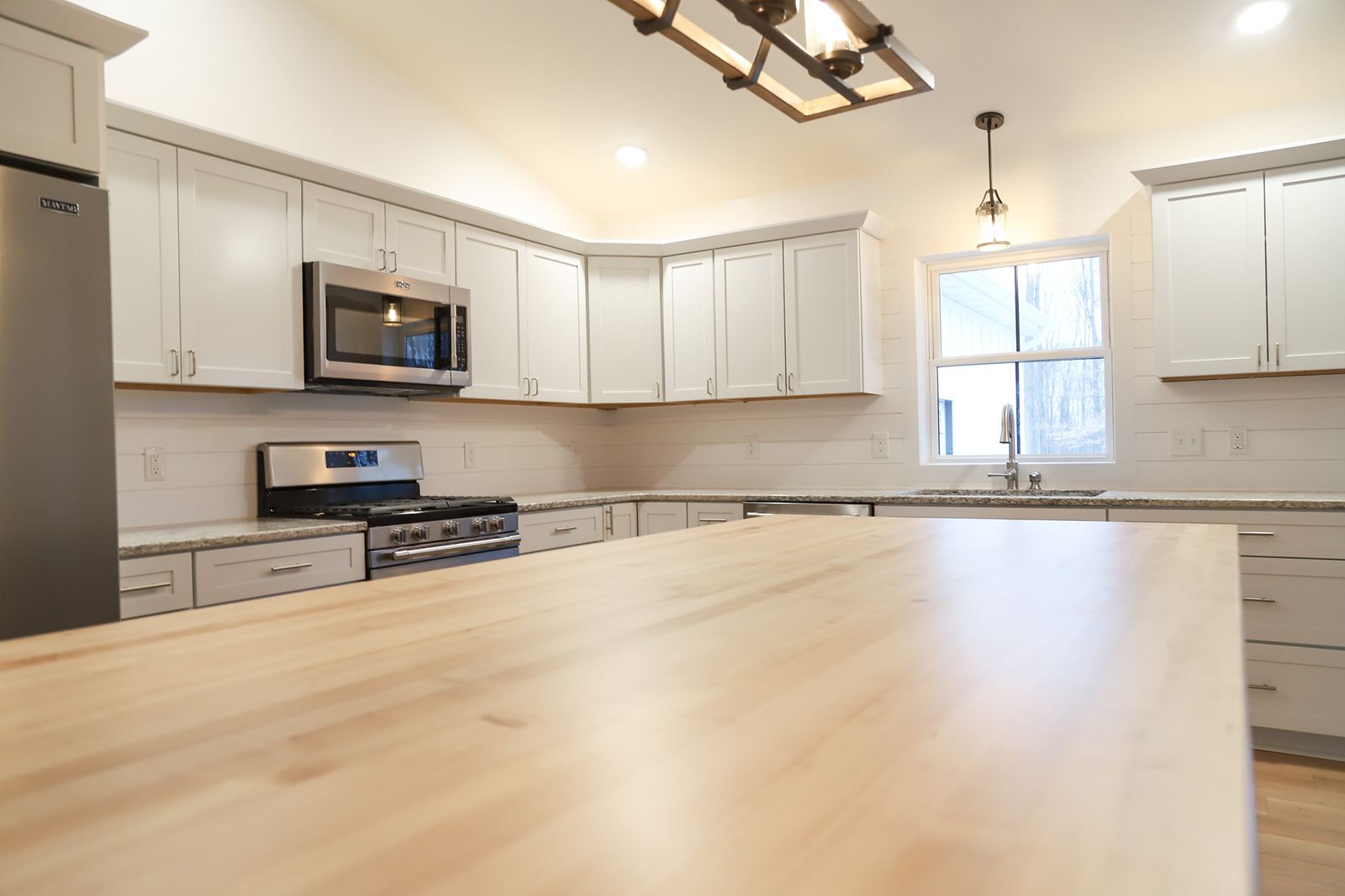 Grey shaker kitchen with a maple butcher block island and shiplap backsplash