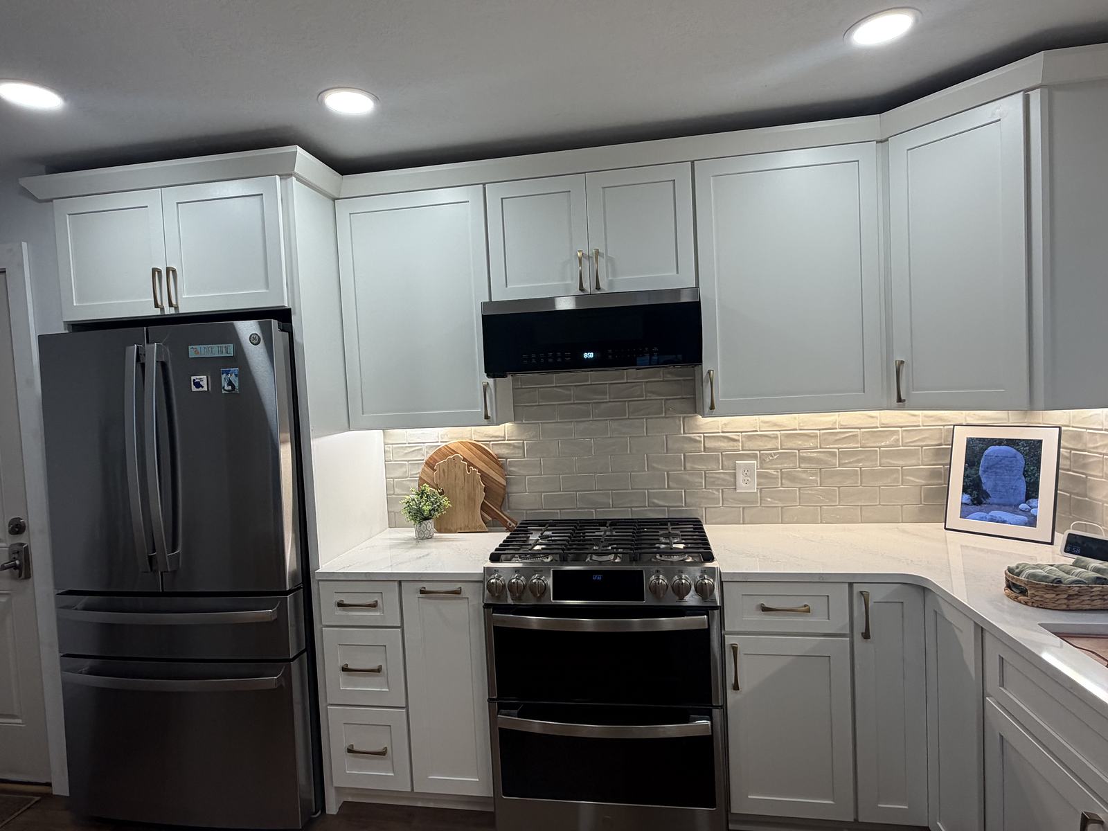 Range wall with cream handmade subway tile, quartz counters and brass pulls