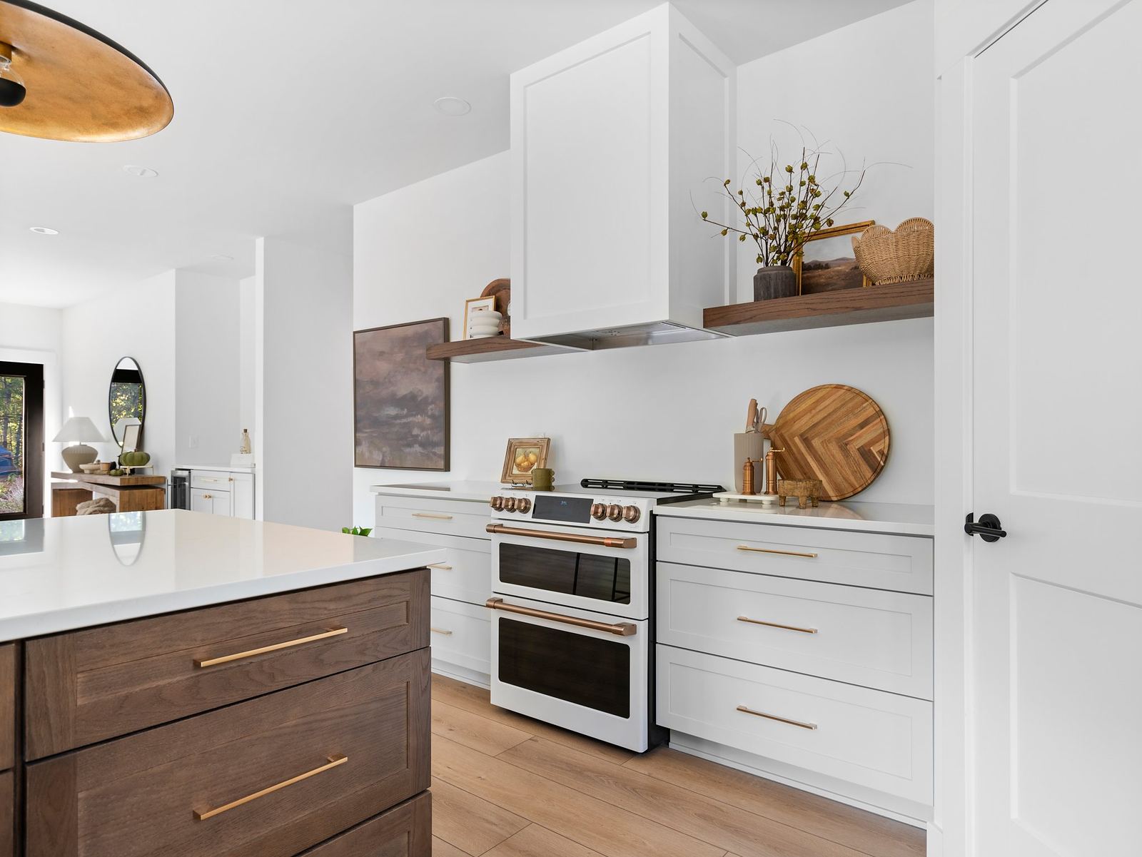 White kitchen with a double oven, custom hood and walnut floating shelves