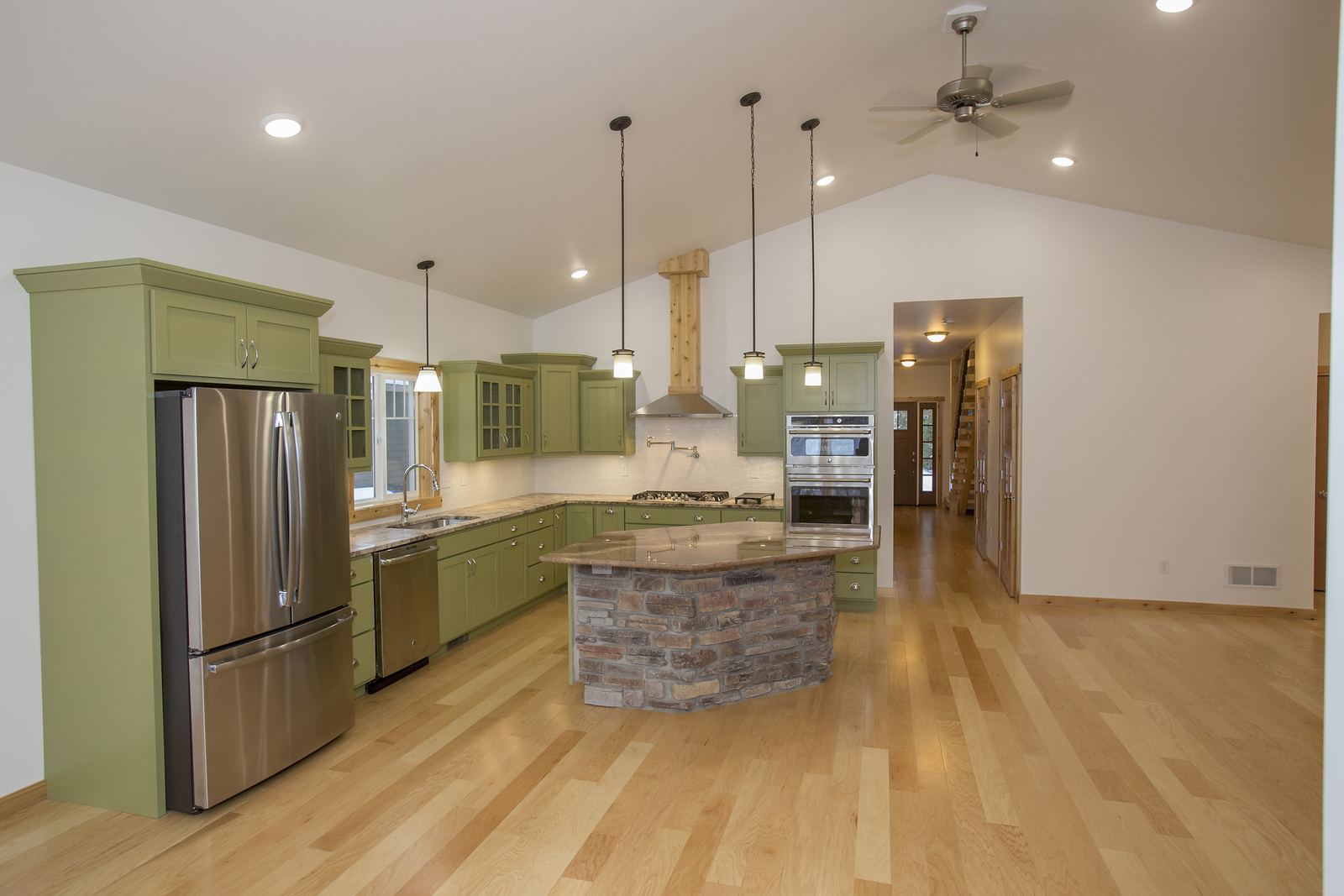 Green kitchen with a reclaimed brick island, double wall ovens and maple floors