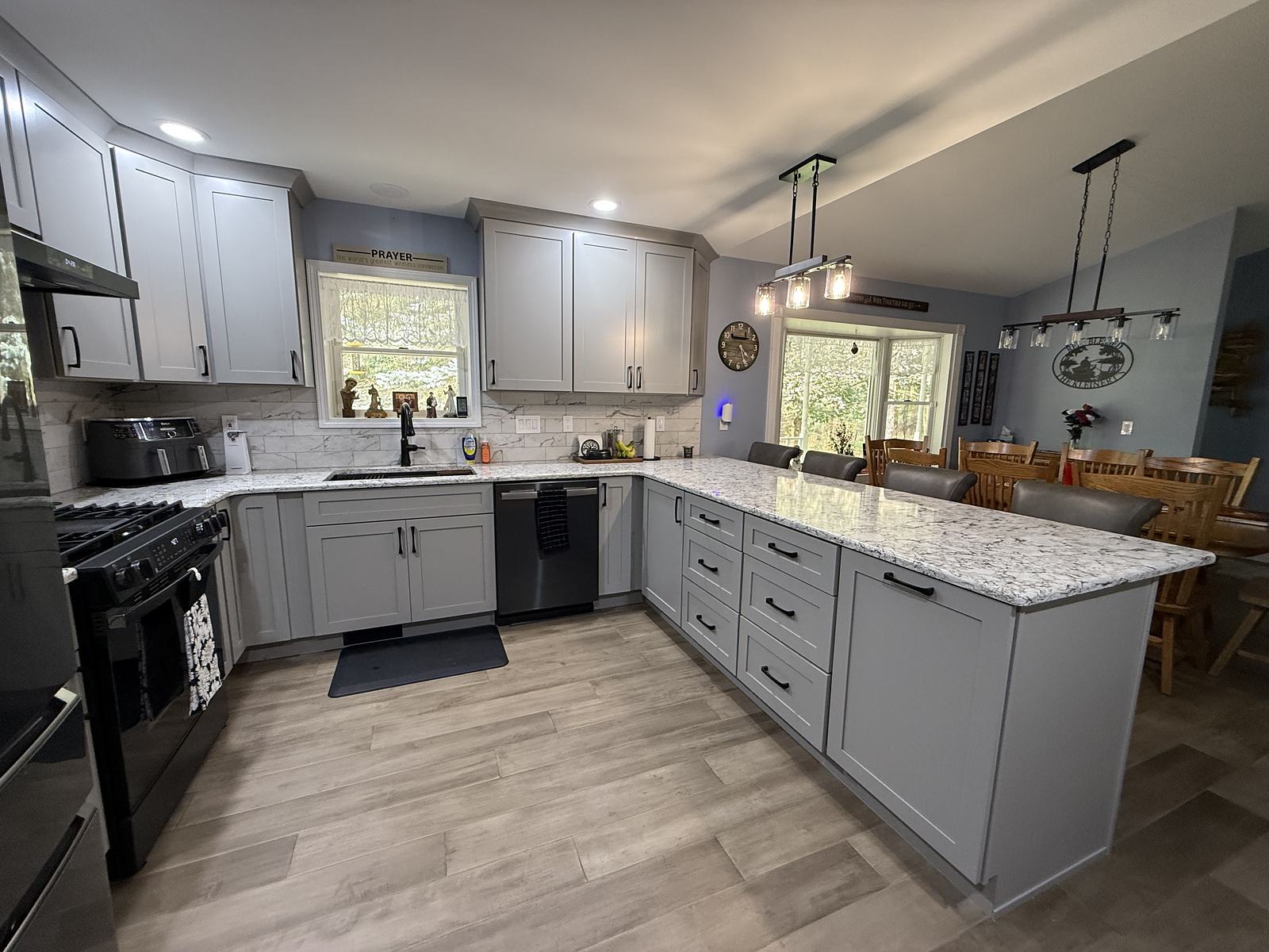 Grey kitchen with a granite peninsula, seating for four and lantern pendants