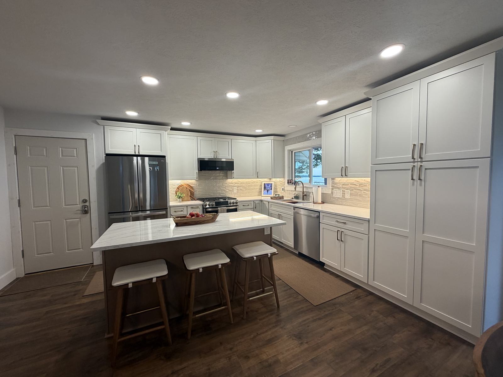White kitchen with a stained island, quartz top and a lake view over the sink