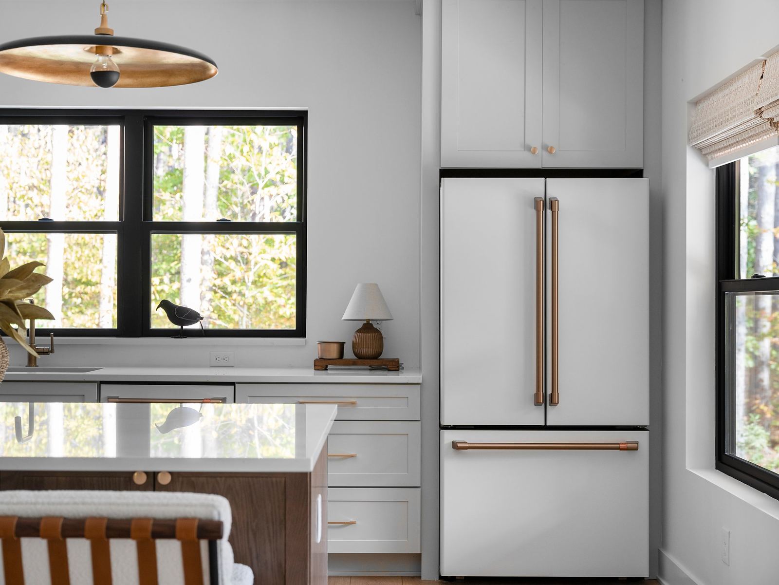Panel-ready refrigerator built into custom cabinetry beside a black-trim window