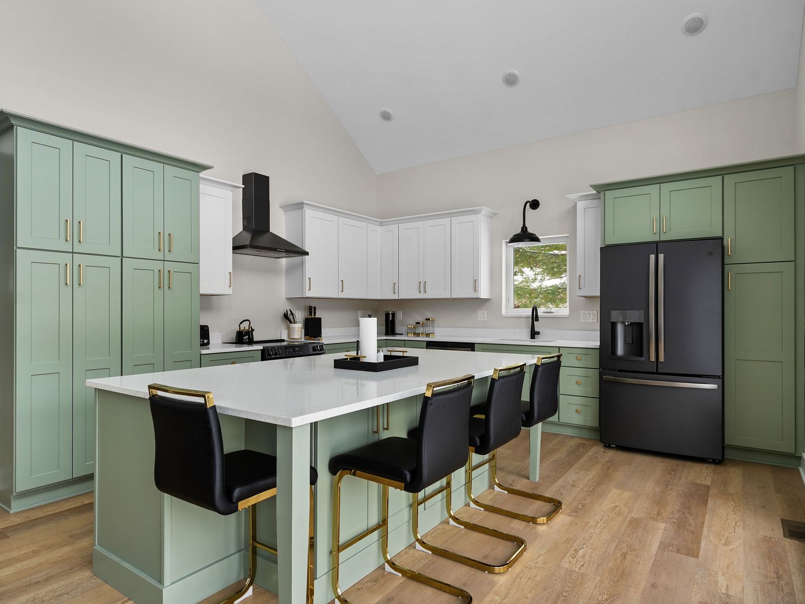 Sage kitchen from the island, with black appliances and gold hardware