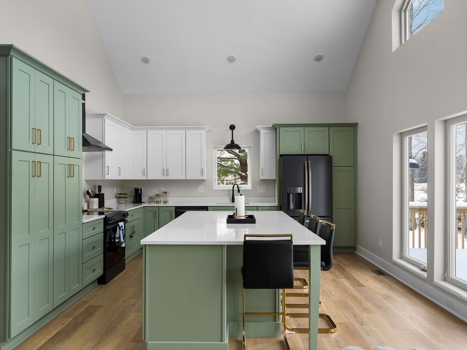 Sage green kitchen with white uppers, quartz island and brass hardware