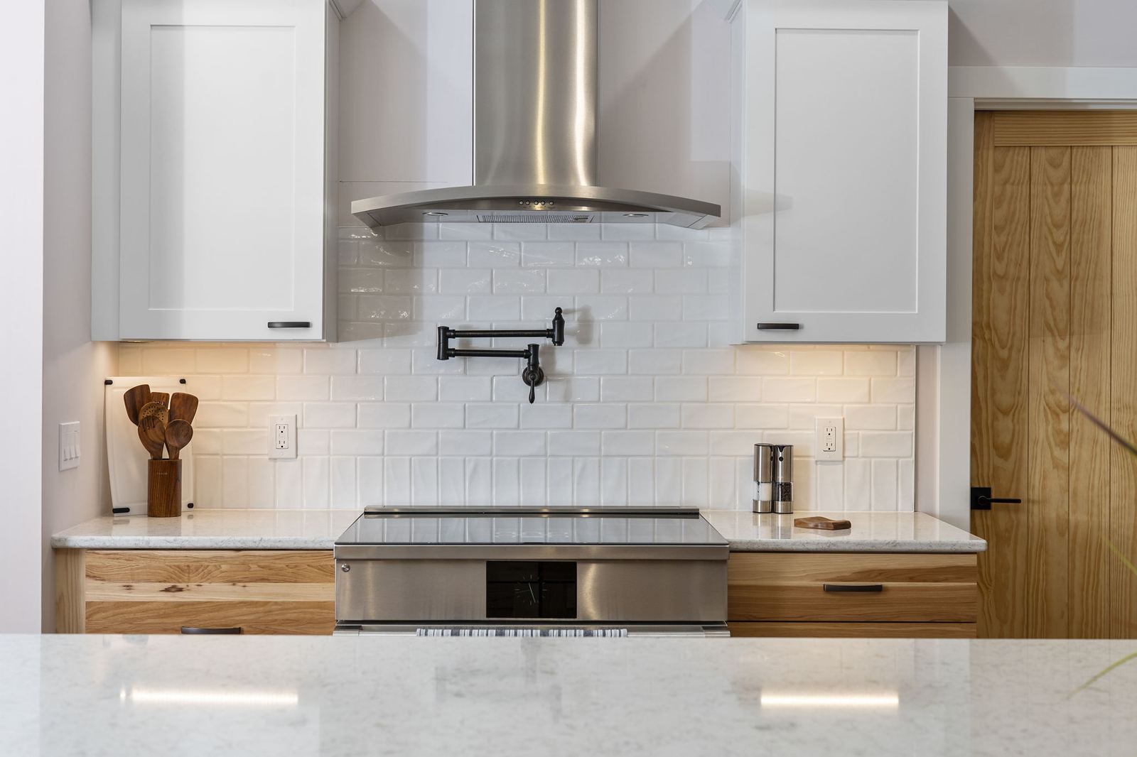 White subway backsplash with a pot filler over an induction range