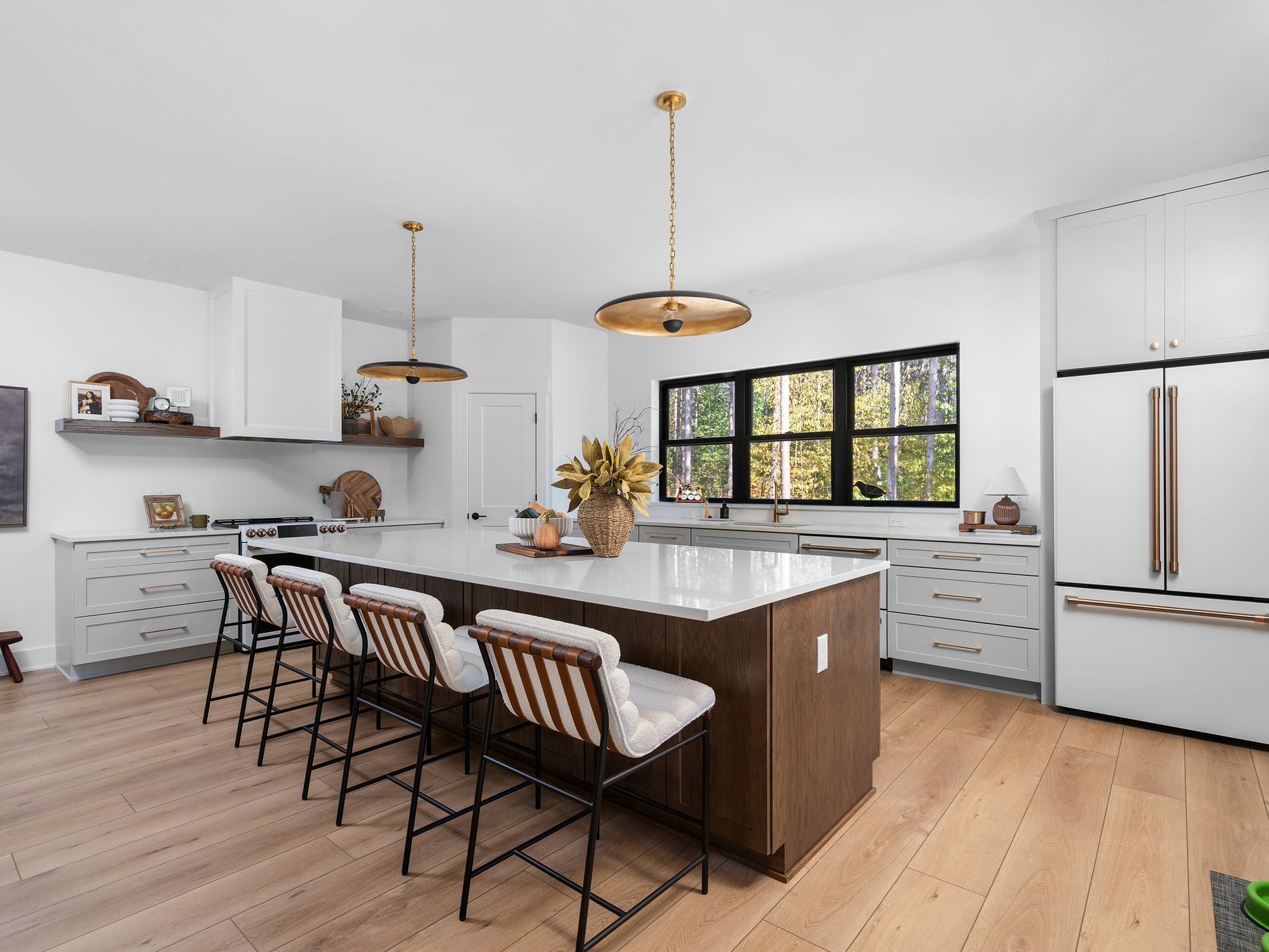 White kitchen with a walnut island, quartz waterfall top and brass pendant lighting