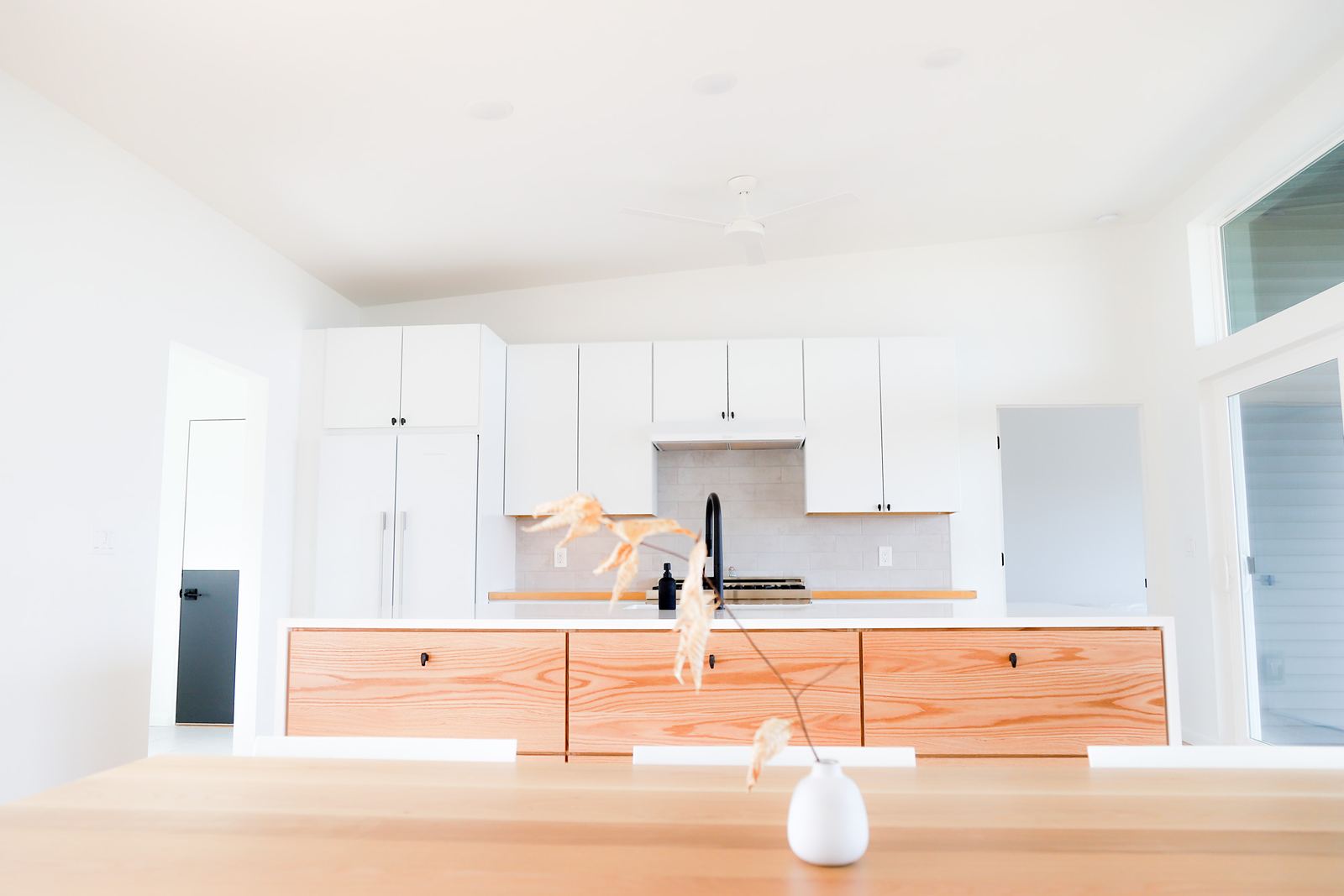 Modern white kitchen with a white oak island front and integrated appliances