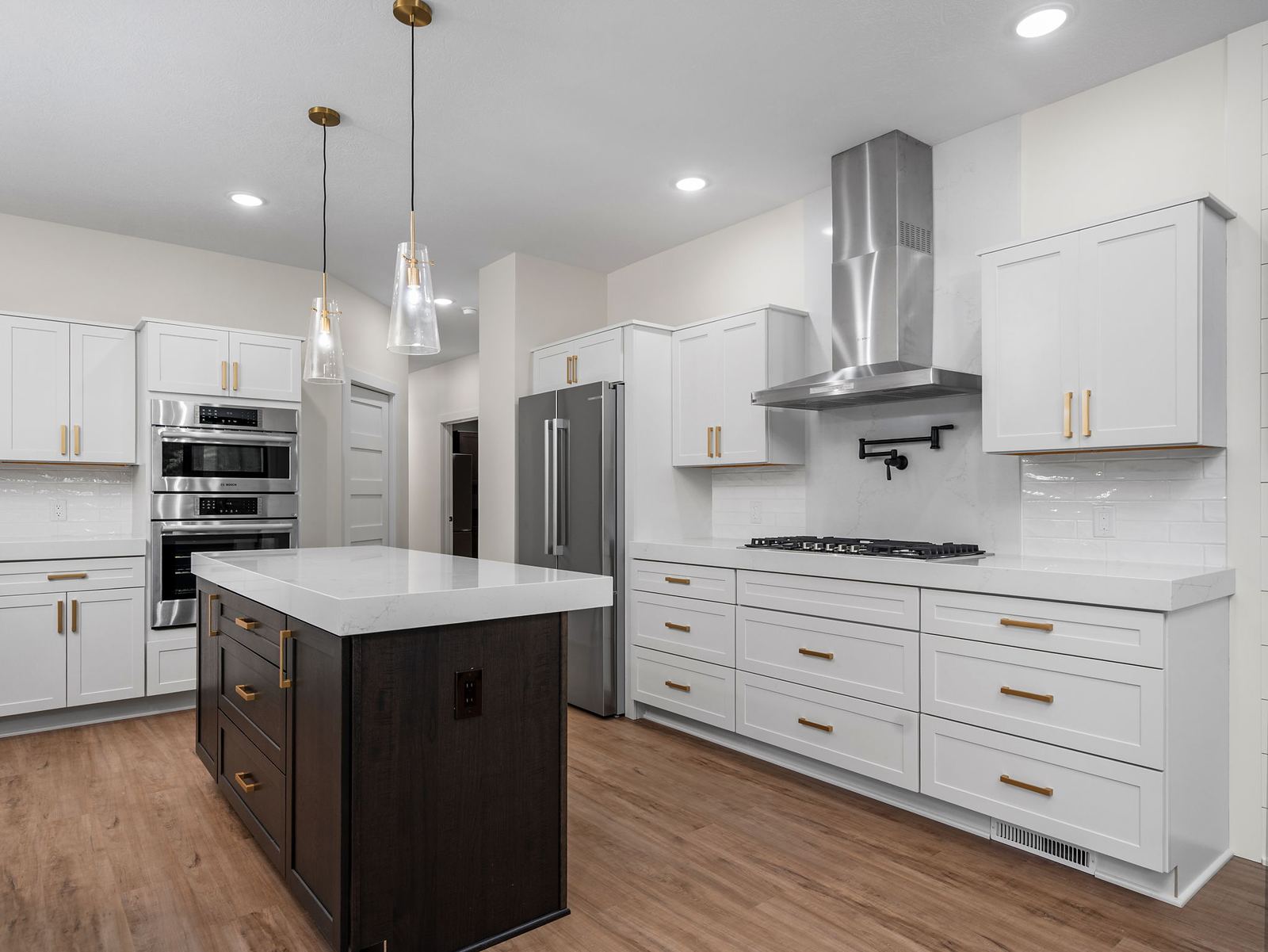 White shaker kitchen with a dark stained island and brass pulls