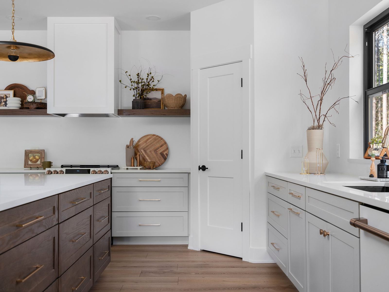 White kitchen with a walnut island, floating shelves and pantry door