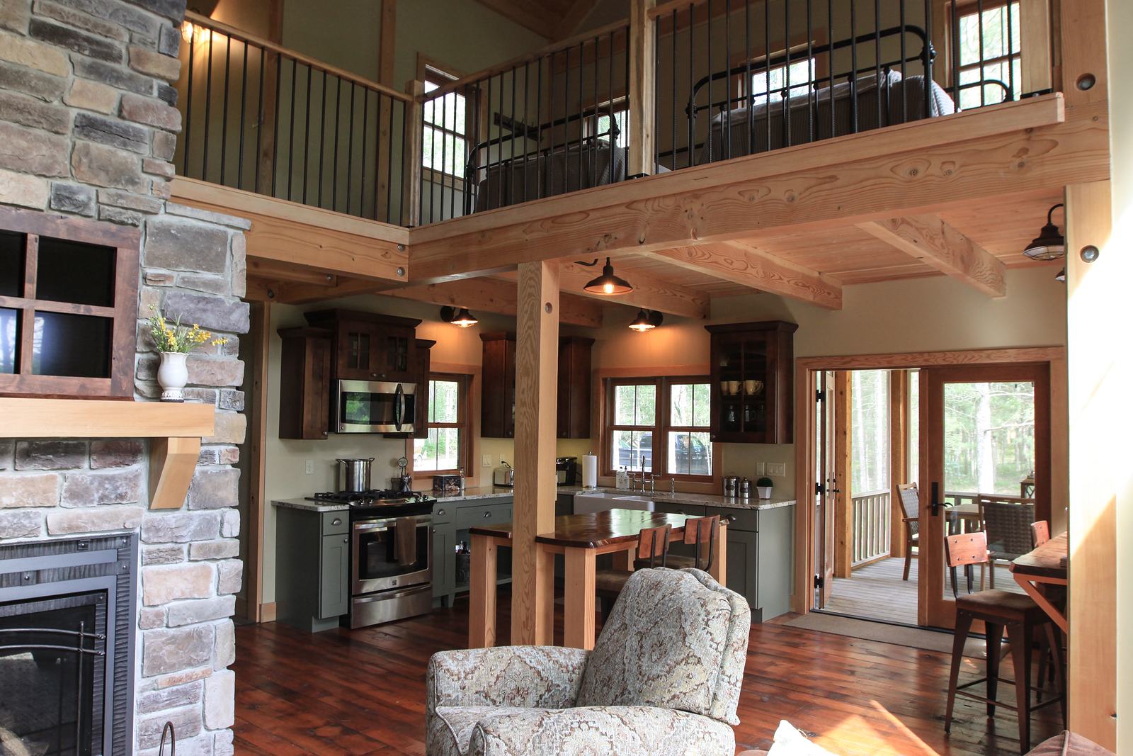 Timber-frame great room with a stone fireplace, sleeping loft and open kitchen