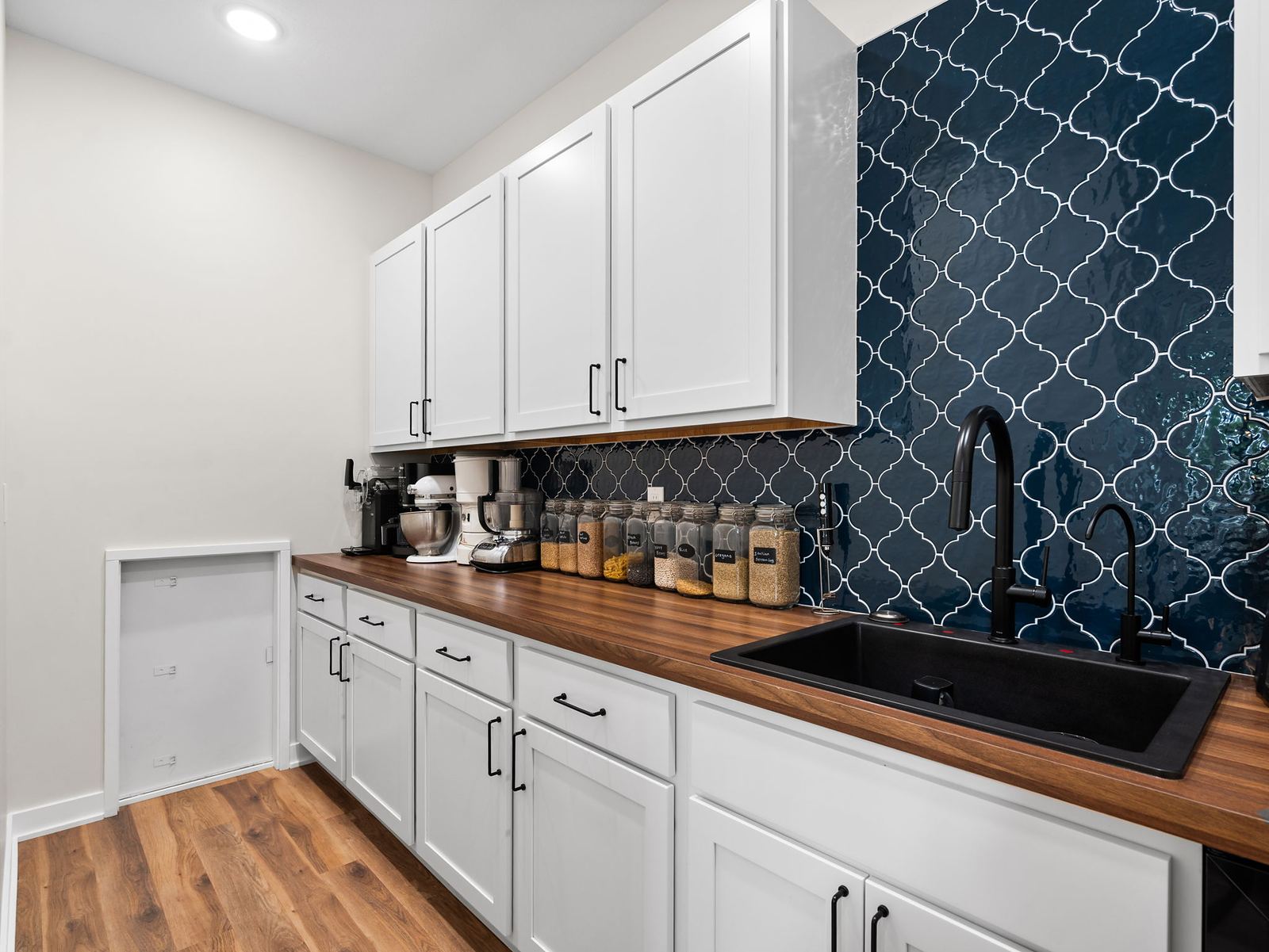 Butler's pantry with a walnut counter, white cabinetry and navy arabesque tile