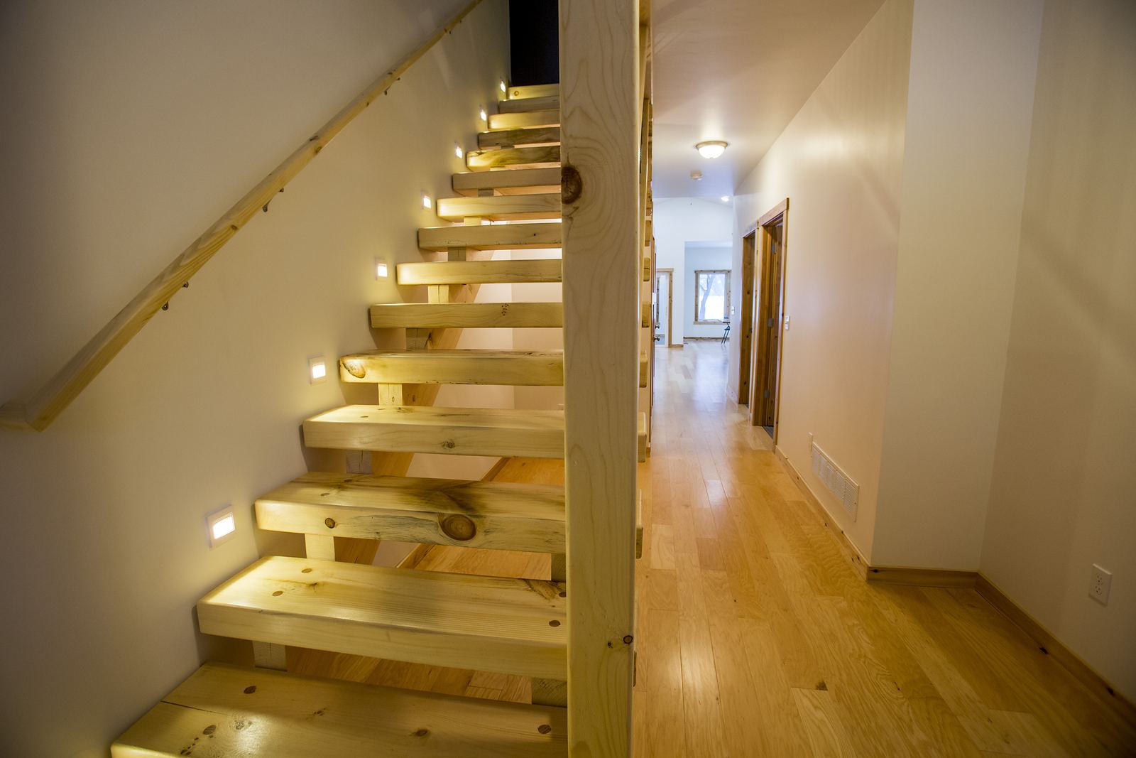 Open-tread pine staircase with recessed step lighting and a hickory floor
